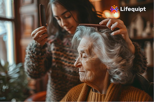 A close-up shot of a younger woman with dark hair and a patterned sweater, gently brushing the gray hair of an older woman wearing an orange sweater. The Lifequipt logo is visible in the upper right corner. The scene appears to be set indoors with warm, soft lighting.